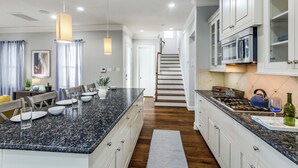 Una cocina moderna con encimeras de granito, muebles blancos y electrodomésticos de acero inoxidable.