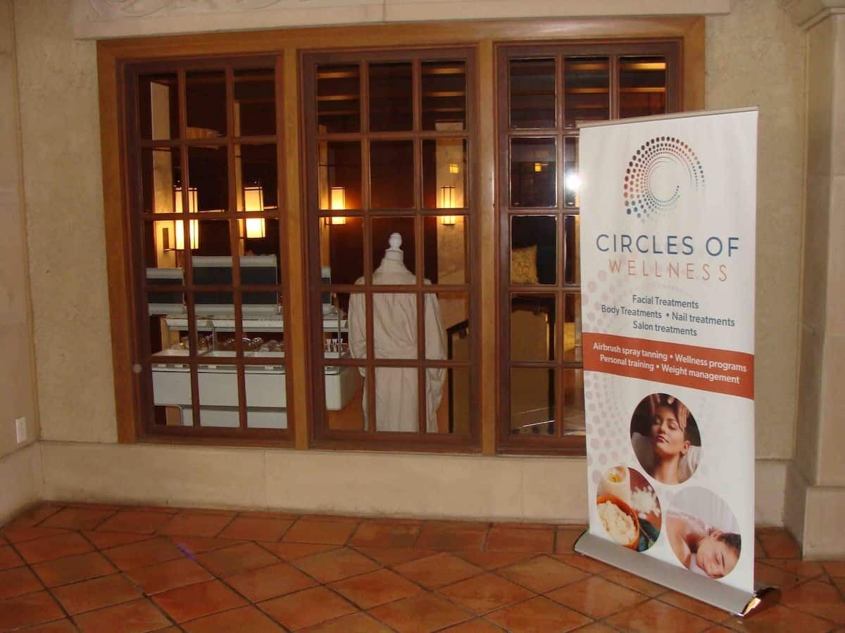 A salon with a large window and a signboard for 'Circles of Wellness' offering various treatments.