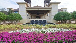 A large, two-story building with a symmetrical facade, a central entrance, and a water feature in front.
