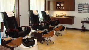 A salon with multiple chairs, a reception desk, and a wall-mounted shelf with items.