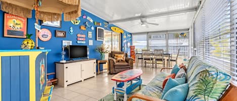 A room with a TV, seating area, and a wall decorated with various signs and pictures.