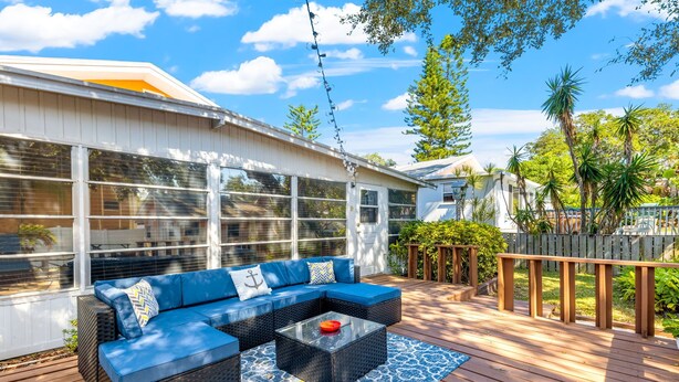 A deck with a blue sofa, a glass coffee table, and a patterned rug. - Vibrant Tropical Escape – Just Minutes from the Beach + Serene, Fenced Yard! (Largo)