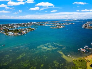 An aerial view of a coastal town with multiple islands connected by bridges, clear blue waters, and a variety of buildings.