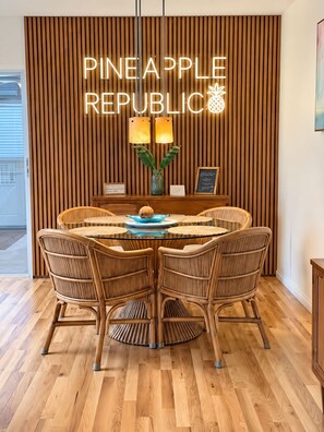 A dining area with a round table, wicker chairs, and a wooden wall with vertical slats. - Vibrant Tropical Escape – Just Minutes from the Beach + Serene, Fenced Yard! (Largo)