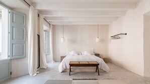 A minimalist bedroom with a large bed, a bench, and a view of the outside. - Meem Townhouse (Sóller)