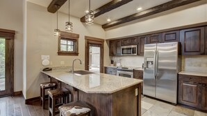 A kitchen with a large island, stainless steel appliances, wooden cabinets, and pendant lighting. - Elegant 3 Bedroom Townhome with Fireplace (Breckenridge)