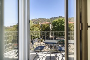A balcony with a table and chairs, overlooking a hillside with buildings and trees. - [DUOMO] Free parking and private terrace (Como)