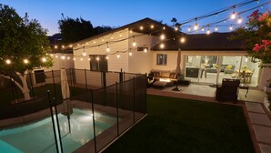 A backyard with a swimming pool, a covered patio, and string lights. - Preserve Oasis-Pool · Casita · Game Room · Treehouse (Phoenix)