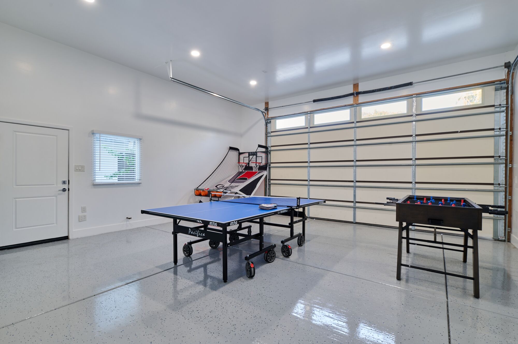 Amplo espaço interno com mesa de pingue-pongue, mesa de futebol de botão e cesta de basquete.