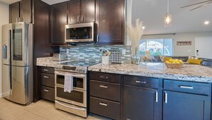 A modern kitchen with dark cabinets, stainless steel appliances, and a granite countertop. - Preserve Oasis-Pool · Casita · Game Room · Treehouse (Phoenix)