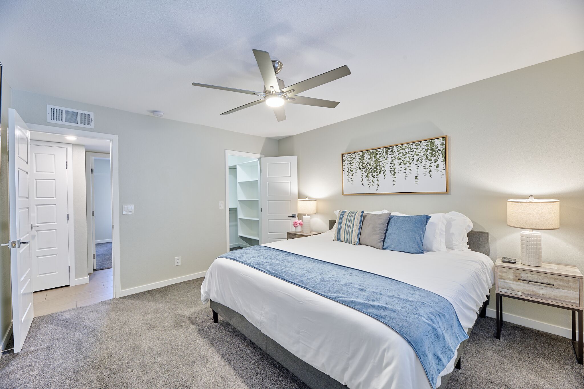 A bedroom with a bed, a ceiling fan, a nightstand, a lamp, and a closet.