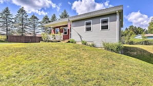 A single-story house with a front porch, a small deck, and a well-maintained lawn. - Sunny Morristown Home - Walk to Restaurants! (Morristown)