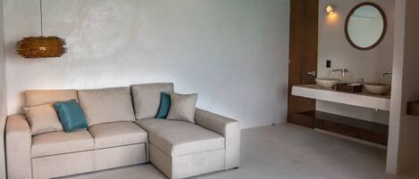 Un baño moderno con un sofá beige, un espejo redondo y un techo de madera.