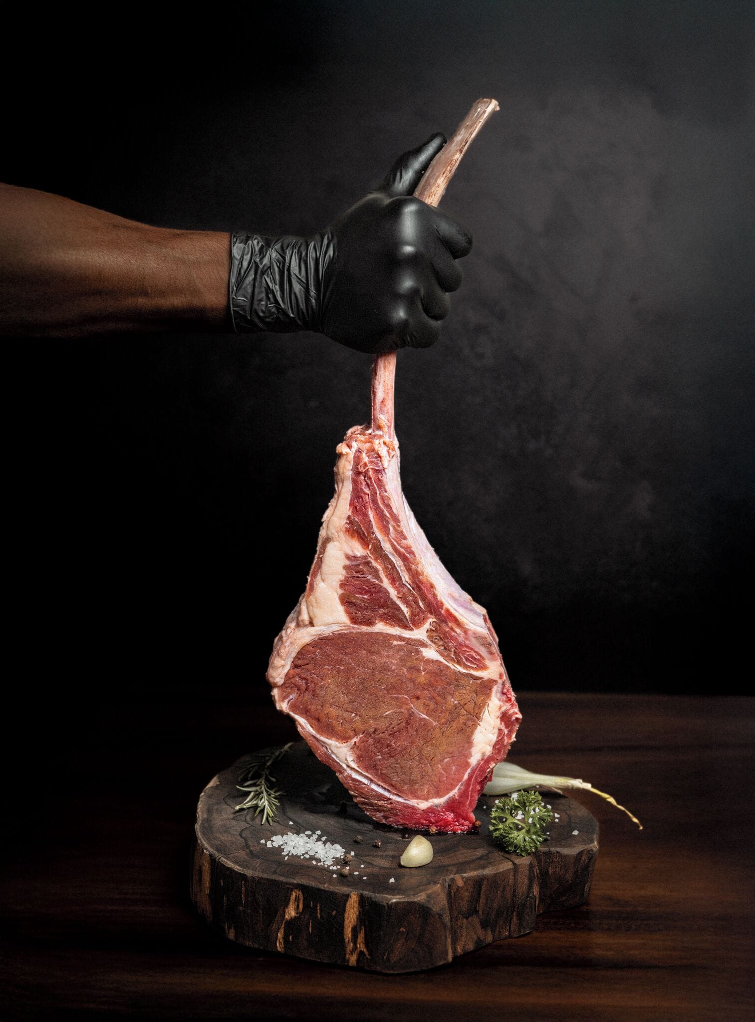 Una persona sosteniendo un gran trozo de carne cruda, posiblemente un bistec, con un cuchillo.
