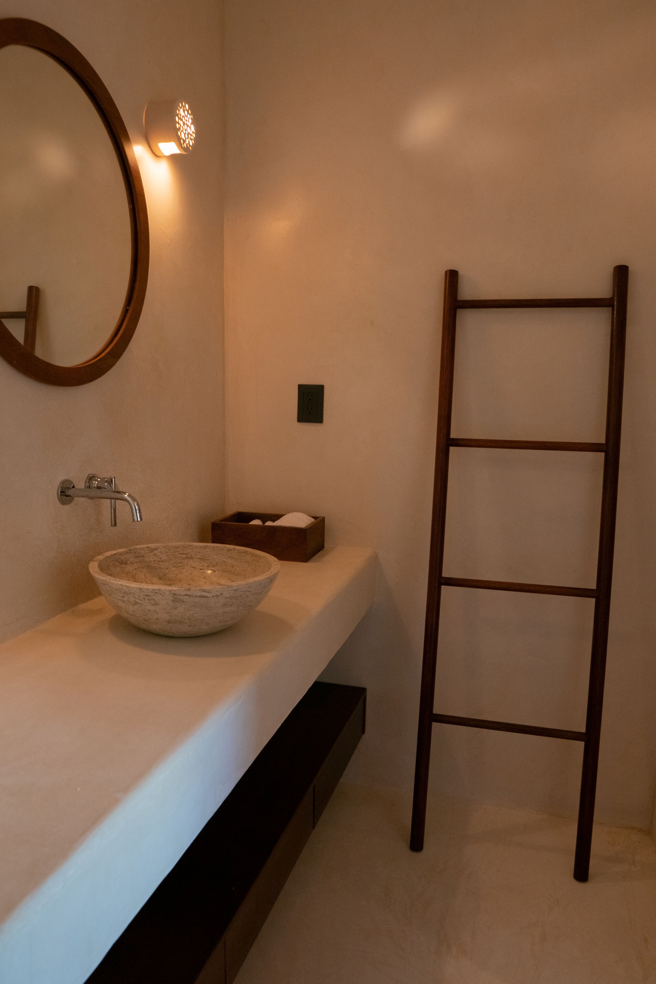 Une salle de bain avec un lavabo rond, un miroir, un porte-serviettes et un savonnière.