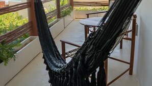 A hammock on a balcony with a view of the sea.
