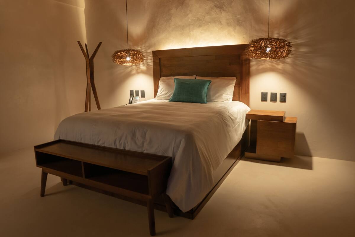 Een moderne slaapkamer met een houten hoofdbord, een nachtkastje en een bankje.