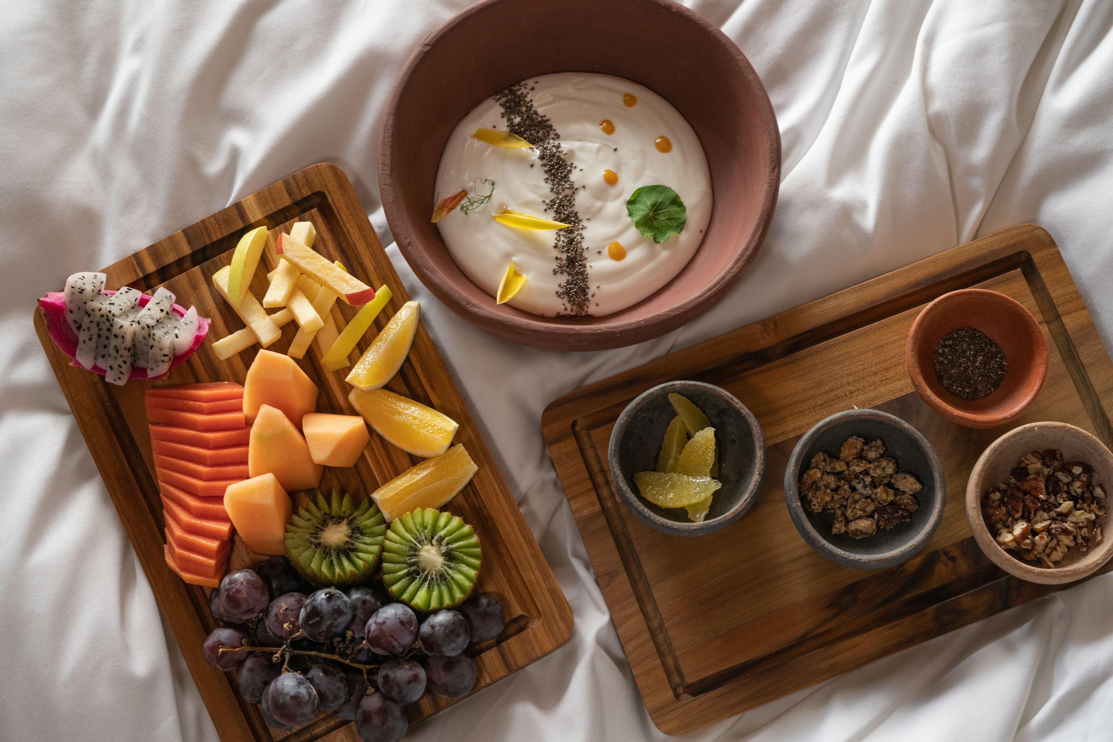 Una tabla de madera con frutas cortadas y un tazón de yogur con semillas.