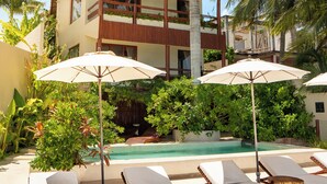 A resort with a pool, lounge chairs, and umbrellas.