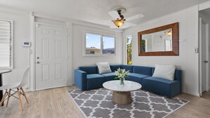 A modern living room with a blue sectional sofa, a round coffee table, and a large mirror.