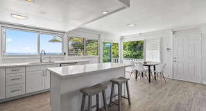Enjoy ocean views from the large windows in this kitchen, featuring a spacious island with bar stools and ample counter space.