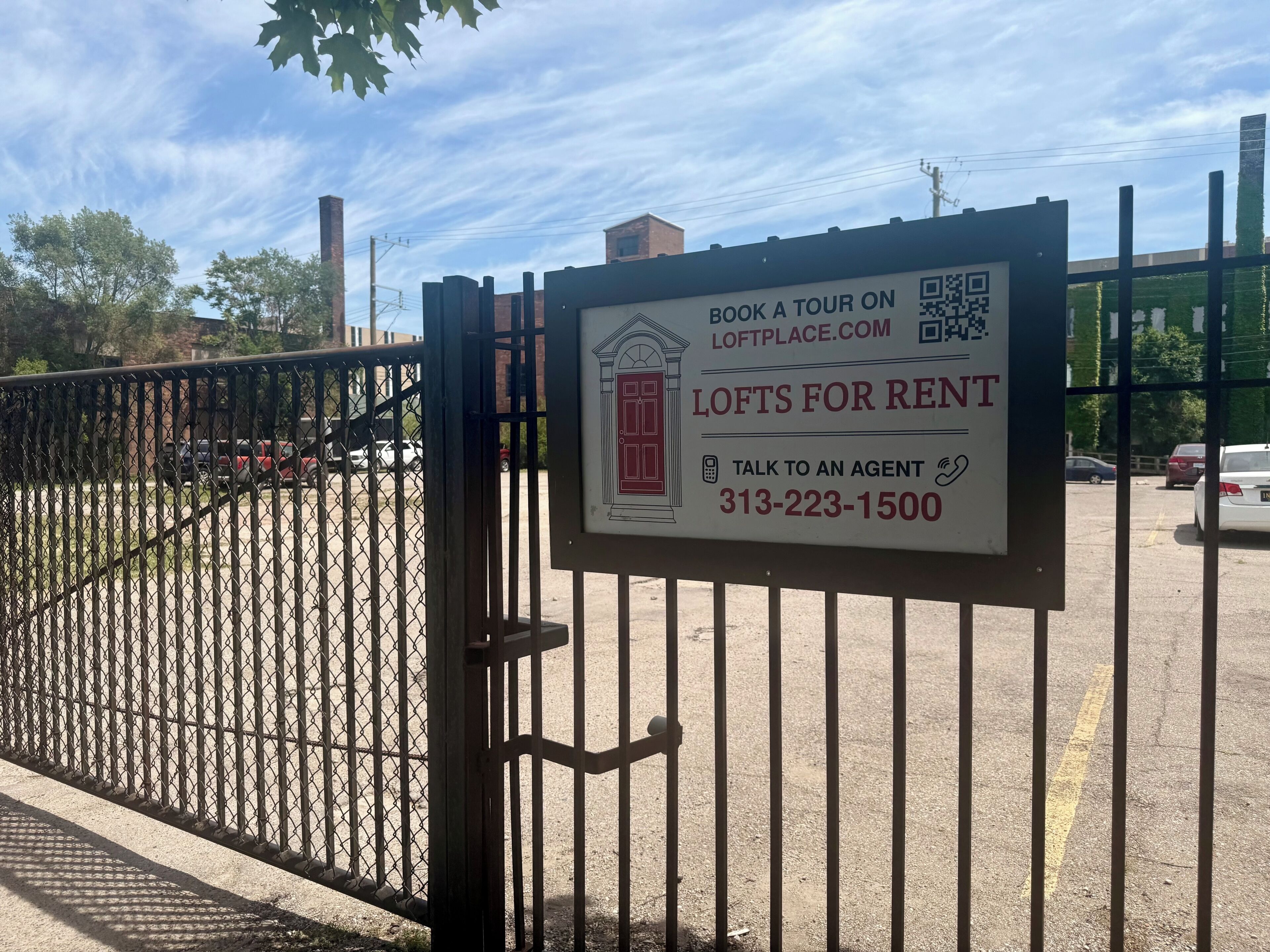 A gated property with a sign advertising lofts for rent and a contact number.