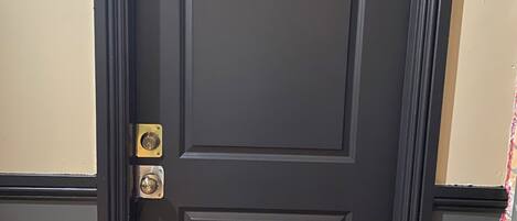 Una puerta de madera oscura con el número 202, un timbre de latón y un felpudo.