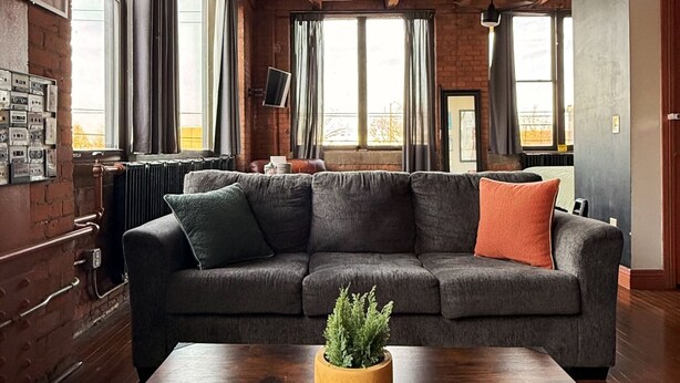 Una sala de estar moderna con un sofá modular, una mesa de centro de madera y un ventilador de techo.