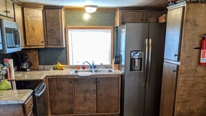 A kitchen with wooden cabinets, a stainless steel refrigerator, a microwave, and a coffee maker.