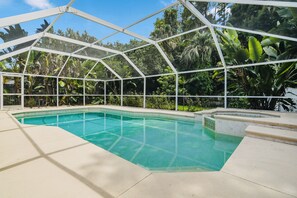 A swimming pool with a glass enclosure, surrounded by lush greenery. - Spacious 2 Story - Pool - Game Room - Tampa (Tampa)