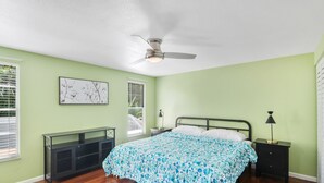 Ein Schlafzimmer mit einem Bett, einem Nachttisch, einer Bank und einem Deckenventilator.