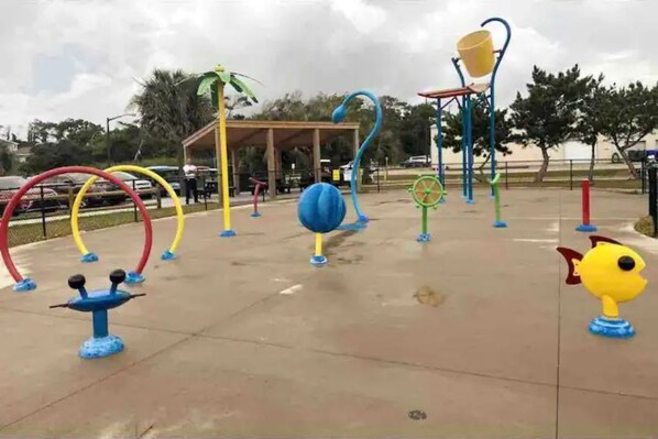 An outdoor playground with various play structures including swings, a climbing frame, and a ball pit.