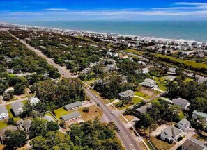 An aerial view of a coastal residential area with houses, roads, and a beach.