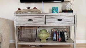 A living room with a flat-screen TV mounted above a wooden console table.