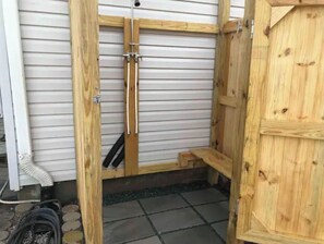 A wooden door with a metal handle, a wooden bench, and a tiled floor.