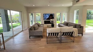 Ein großzügiges Wohnzimmer mit großem Fernseher, zwei Sofas und einem Couchtisch.
