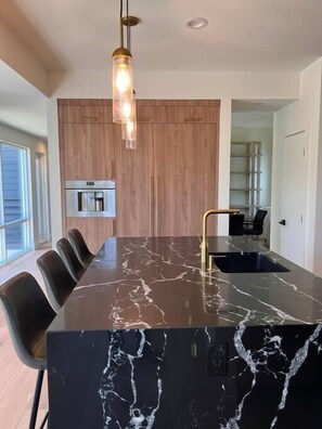 A modern kitchen with a large island, wooden cabinetry, and a built-in oven. - Gorgeous New "Cosmopolitan Arts House" in Prime Silverlake with Pool and Views! (Los Angeles)