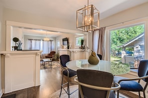Relax in a stylish living area with a central table, comfortable chairs, and a large window offering a view of the surrounding landscape.
