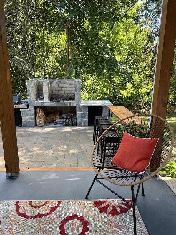 An outdoor patio with a stone fireplace, seating area, and a patterned rug. - Beautiful and modern 3 Bedroom 2 full BR. (Marlborough)