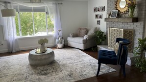 A living room with a fireplace, a sofa, a blue armchair, and a chandelier.