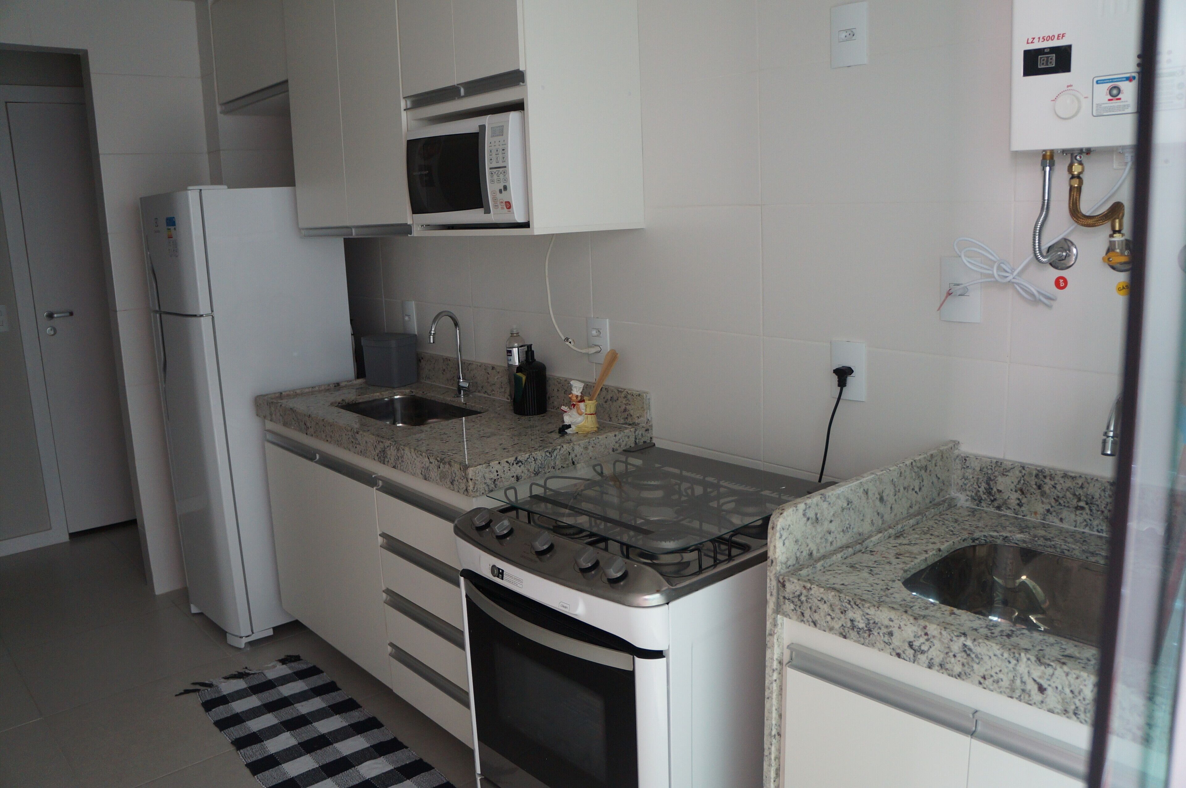 A kitchen with white cabinets, a microwave, a gas stove, and a sink.