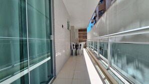 Un couloir aux murs en verre, doté d’un sol carrelé et d’une rambarde sur un côté.