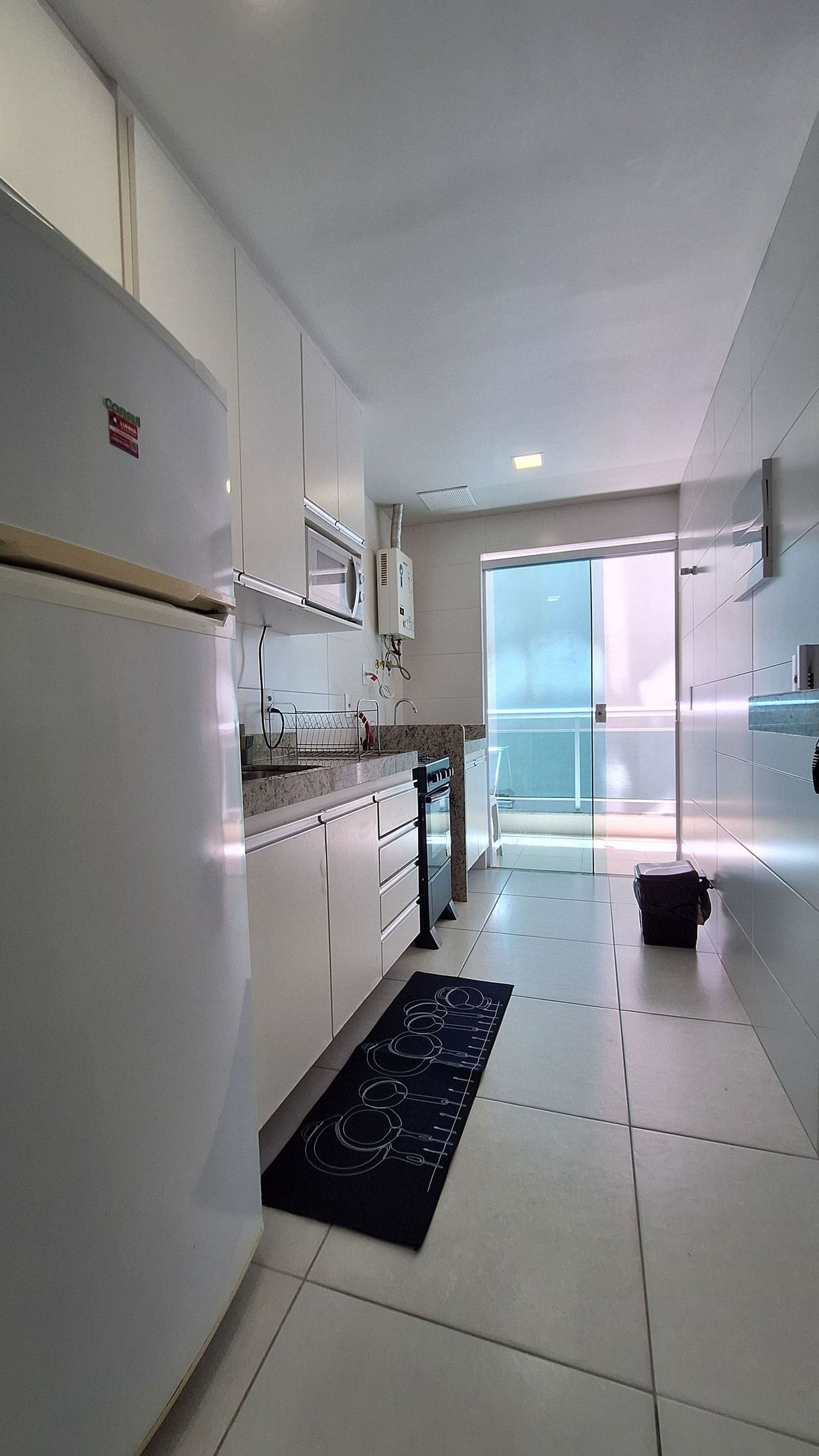 A modern kitchen with white cabinets, a stainless steel refrigerator, and a microwave.