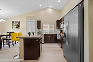 Enjoy cooking in this well-equipped kitchen with a central island, stainless steel appliances, and a dining area nearby.