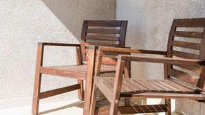 Three wooden chairs with slatted backs and armrests, positioned against a textured wall. - GuestReady - Modern apt near Matosinhos Beach (Matosinhos)