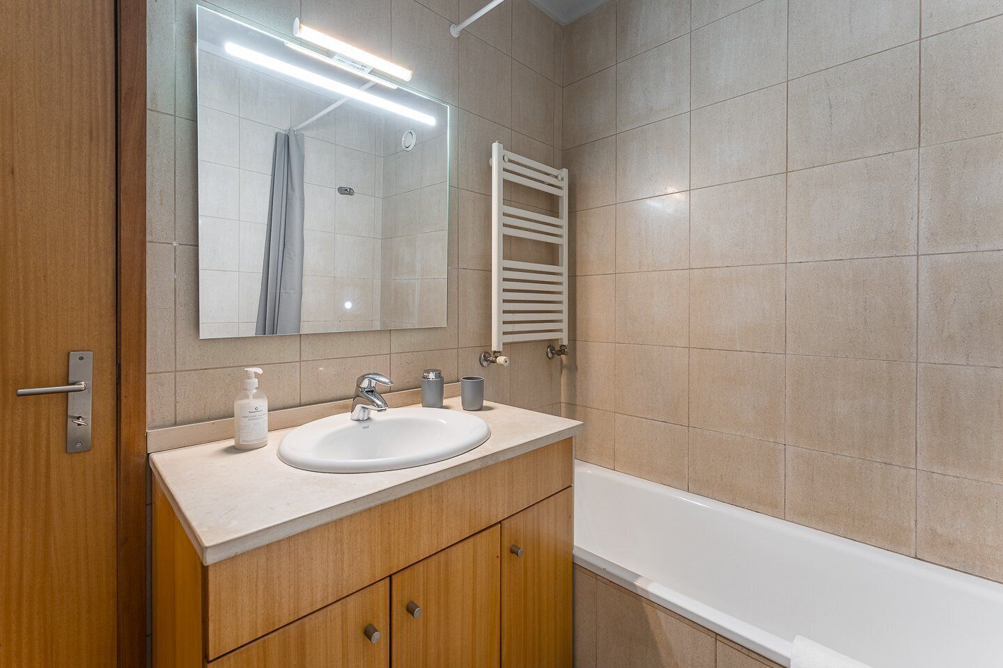 Un baño moderno con lavamanos, espejo y toallero blancos.