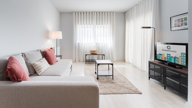 A modern living room with a sofa, a TV, and a dining area. - GuestReady - Modern apt near Matosinhos Beach (Matosinhos)