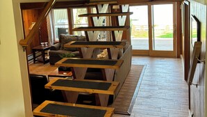 Amplia sala de estar con una escalera de madera, un sofá y un adorno de pared.