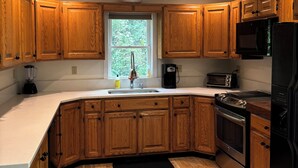 Una cocina con gabinetes de madera, un fregadero, una estufa, un microondas y un tostador.