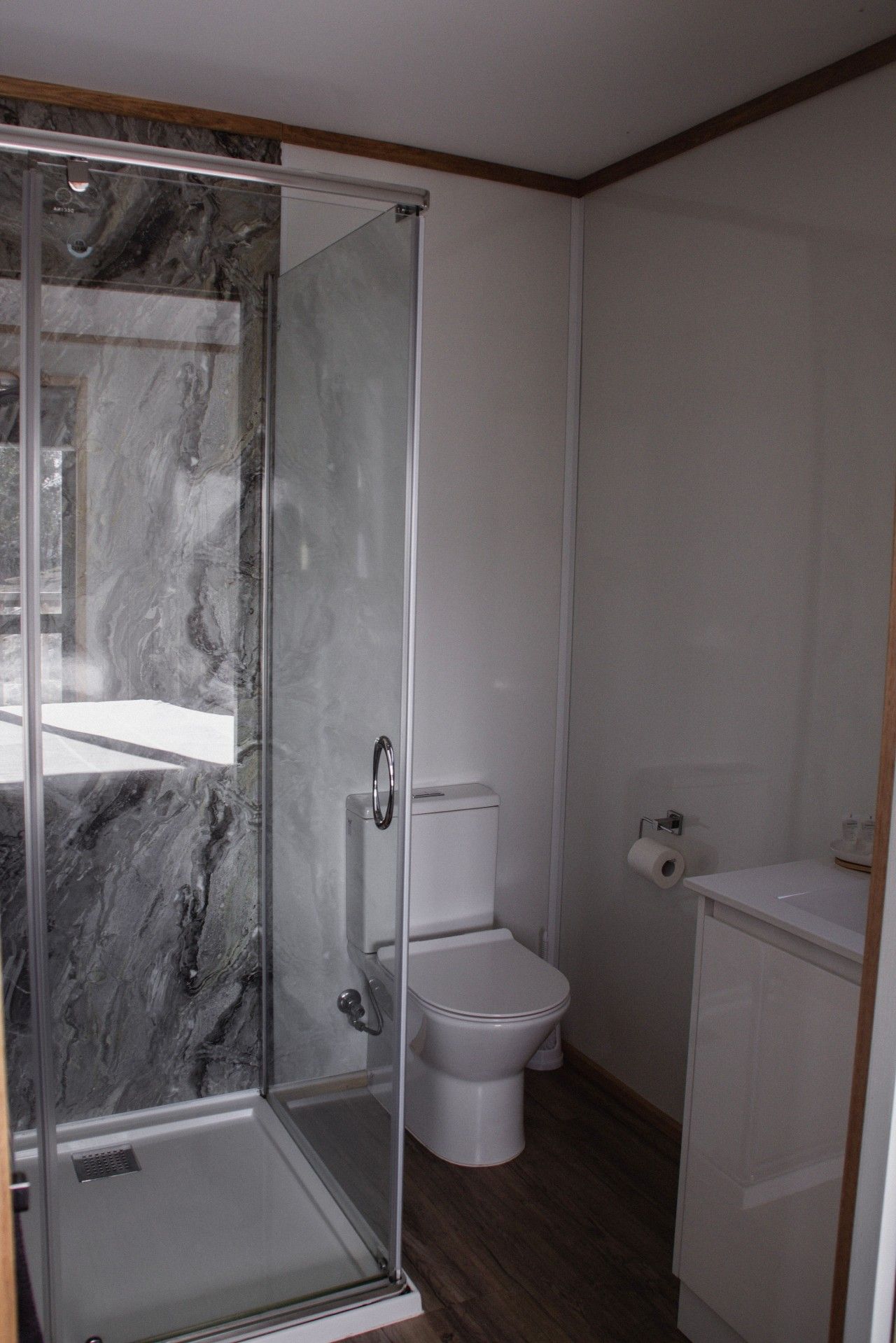 A bathroom with a glass-enclosed shower, a toilet, and a sink.